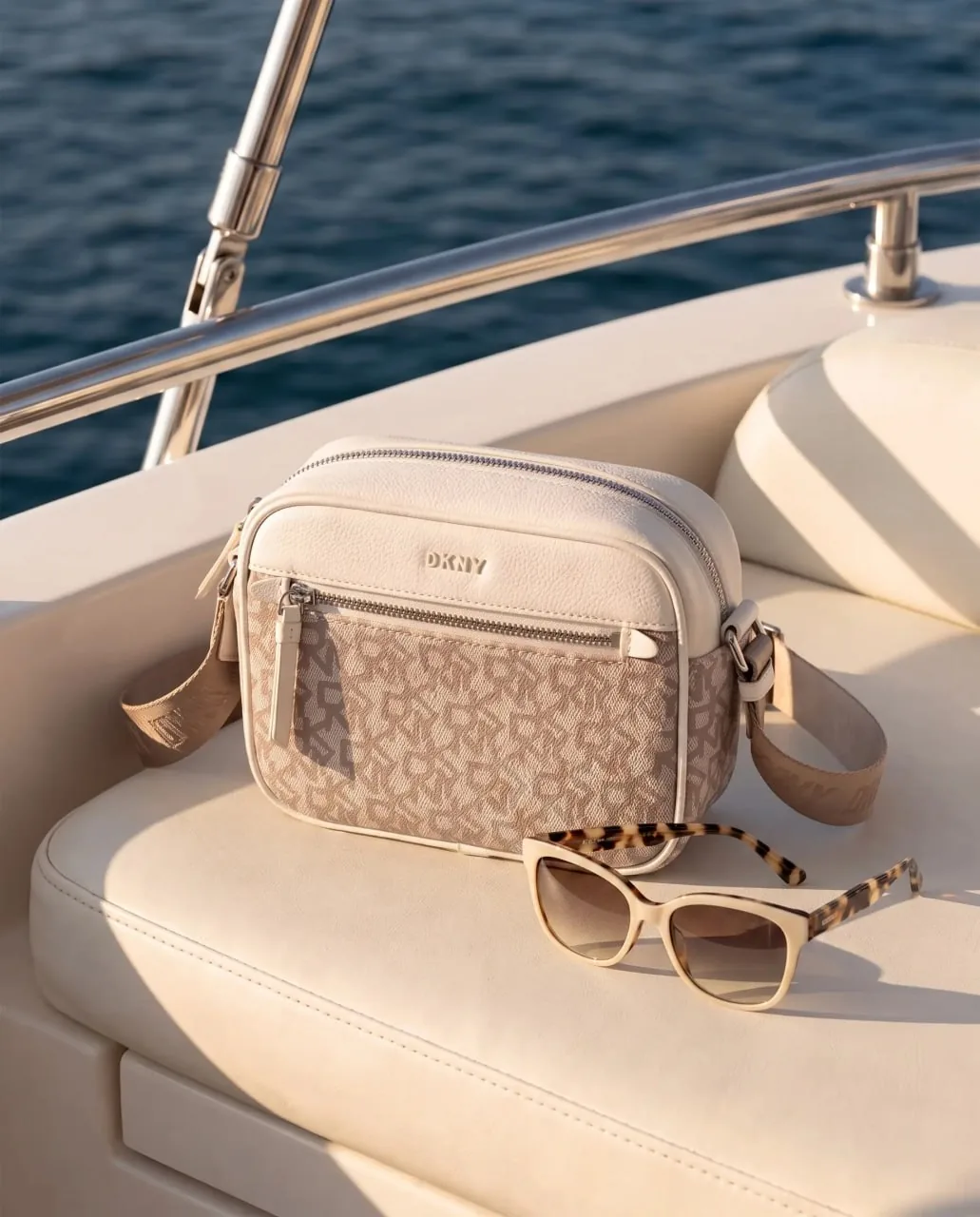 Sac DKNY crème signature sur la banquette d'un yacht, lumière dorée